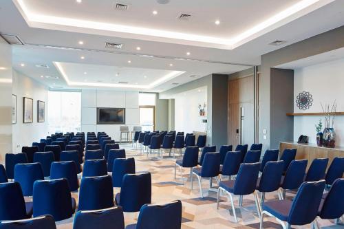 a conference room with blue chairs and a podium at Courtyard by Marriott Oxford South in Abingdon