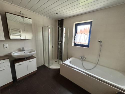 a bathroom with a sink and a tub and a shower at Ferienhaus Auszeit am See in Walchum
