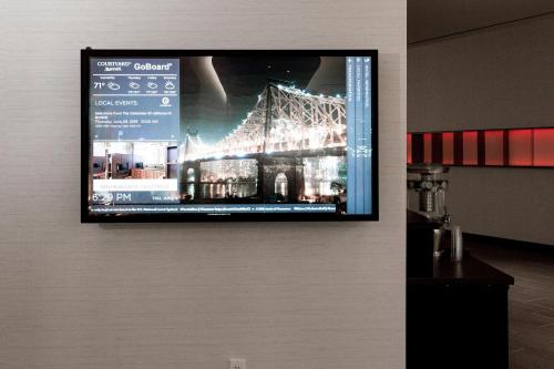 a tv on a wall with a picture of a bridge at Courtyard by Marriott Long Island City/New York Manhattan View in Queens