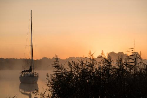 a sail boat on the water at sunset at Dadajowa Osada - Dadaj in Biskupiec