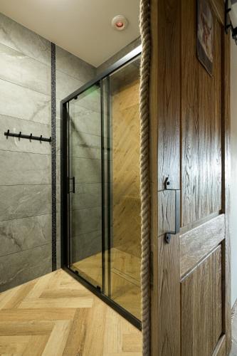 a glass shower in a room with a wooden door at Dadajowa Osada - Dadaj in Biskupiec