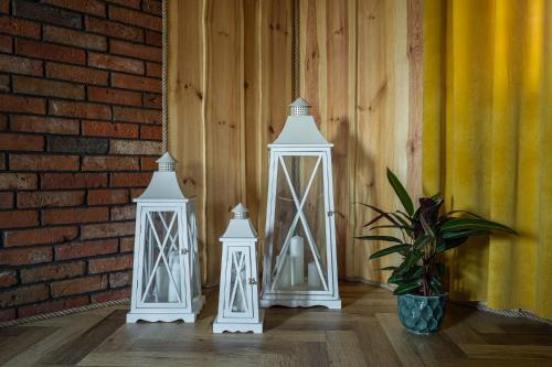 three white lanterns sitting next to a brick wall at Dadajowa Osada - Dadaj in Biskupiec