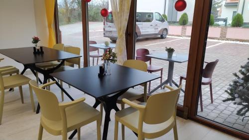 a restaurant with tables and chairs and a window at Végvár Spa Apartman in Gyula