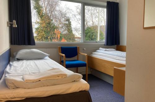 a room with two beds and a chair and a window at BB-Hotel Frederikshavn Turisthotellet in Frederikshavn