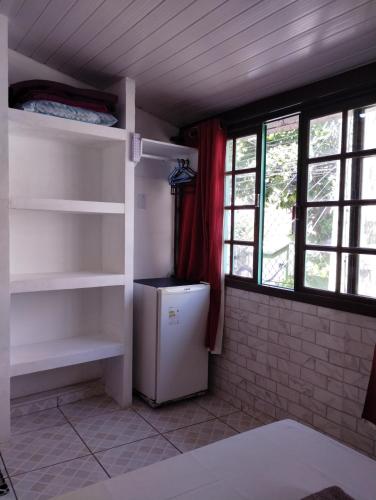 a kitchen with a refrigerator in a room with windows at Canto da Arte - Hospedagem Domiciliar in Cabo Frio