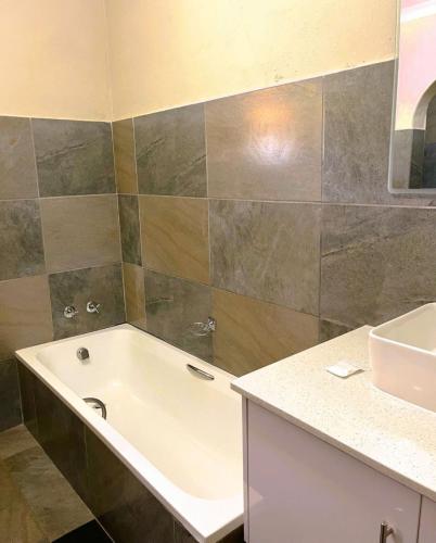 a bathroom with a bath tub and a sink at Hlalanathi Drakensberg Resort in Bergville