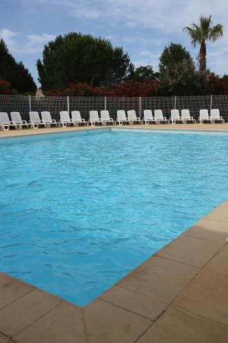 a swimming pool with lounge chairs and a swimming pool at Hôtel Restaurant Les Jasses de Camargue in Gallargues-Le-Montueux