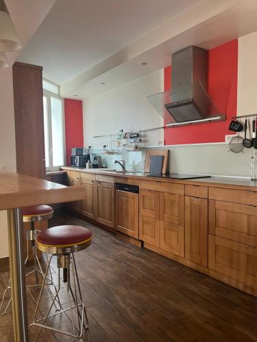 une grande cuisine avec des placards en bois et des murs rouges dans l'établissement La maison perchée, au Puy-en-Velay
