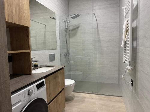 a bathroom with a shower and a washing machine in it at NOMAD APARTMENTS in Mažeikiai