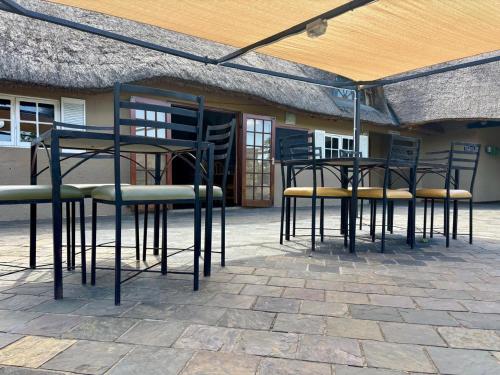 a group of chairs and tables in front of a building at Hlalanathi Drakensberg Resort in Bergville