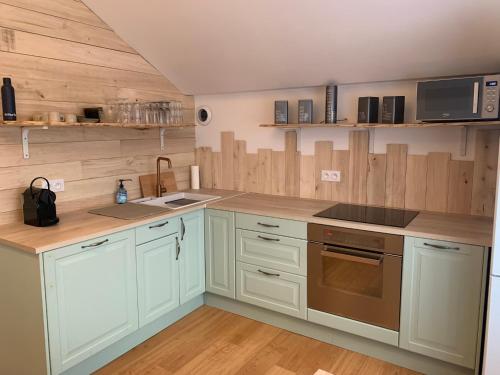 - une cuisine avec des placards blancs et des murs en bois dans l'établissement Maison du Bonheur, gîte Les Collines, à Le Pin