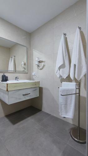 a bathroom with a sink and a mirror and towels at Alojamientos Rurales Las Candelas in Santa Marta de Magasca