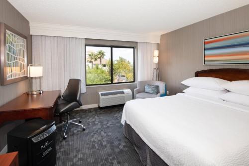 a hotel room with a bed and a desk and a window at Courtyard by Marriott Oakland Airport in Oakland