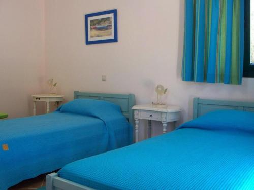 a room with two blue beds and two tables at Sami Beach Villas Fedra in Sami