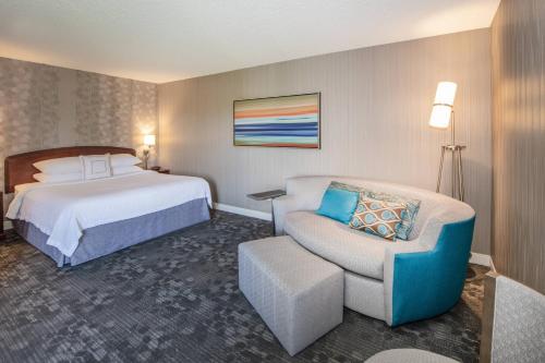 a hotel room with a bed and a chair at Courtyard by Marriott Oakland Airport in Oakland