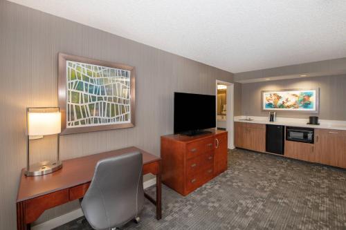 a hotel room with a desk and a television at Courtyard by Marriott Oakland Airport in Oakland