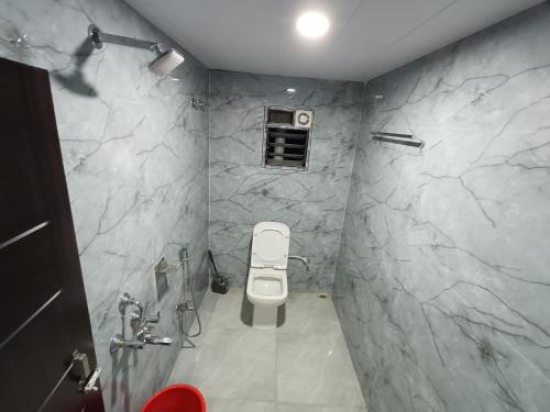 a bathroom with a toilet and a stone wall at Areca Homestay in Guwahati