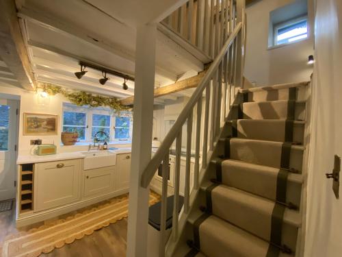 a staircase leading up to a kitchen with white cabinets at The Cottage on the Island in Castleton