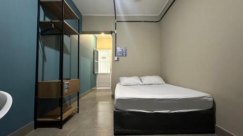 a small room with a bed and a sink at Suíte 03 • Praia das Pitangueiras in Guarujá