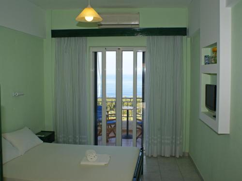 1 dormitorio con cama y vistas a un balcón en Ferouli Residence, en Rizá