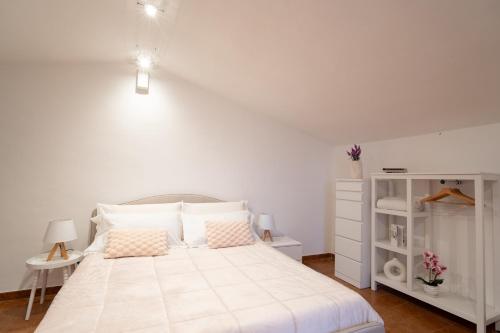 a white bedroom with a large white bed with pink pillows at Villa del Pino, Terrazza vista Mare in Minturno