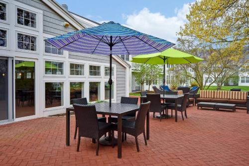 eine Terrasse mit Tischen, Stühlen und Sonnenschirmen in der Unterkunft Courtyard Cape Cod Hyannis in Hyannis