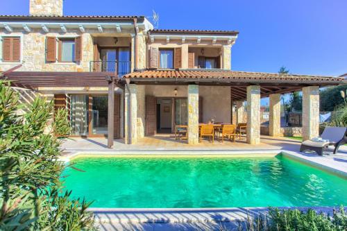 a villa with a swimming pool in front of a house at Villa Fina in Malinska