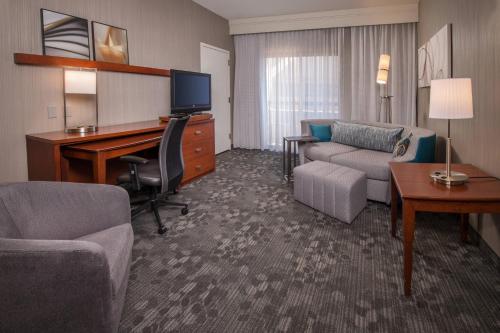 ein Hotelzimmer mit einem Schreibtisch und einem Wohnzimmer in der Unterkunft Courtyard by Marriott Dulles Airport Chantilly in Chantilly
