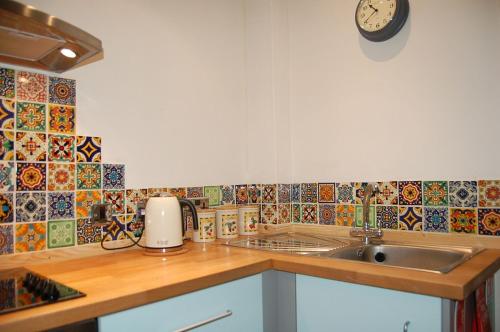 a kitchen with a sink and a clock on the wall at Cysgod Idris Cottage in Dolgellau