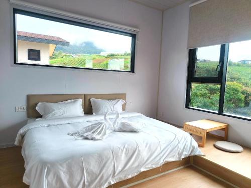 a bedroom with a white bed with a large window at The Pampines Villa, Mount Kinabalu in Ranau