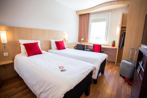 a hotel room with two beds with red pillows at Ibis Hotel Plzeň in Plzeň
