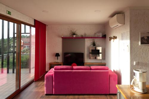 a pink couch in a living room with a tv at Ecofurtado in Furtado