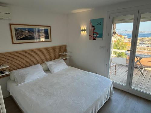 - une chambre avec un lit blanc et un balcon dans l'établissement Au cœur du Parc National du Massif des Calanques, la Flibuste des Goudes, Maison 2 chambres, climatisée, jardins, solarium, proche plage, large vue mer, à Marseille