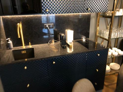 La salle de bains est pourvue d'un comptoir noir et d'un lavabo. dans l'établissement 21a Maréchal FOCH Avenue Paris CHAMPS-ELYSÉES, à Paris