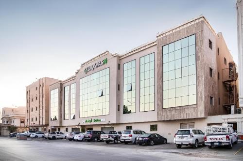 a large building with cars parked in a parking lot at Wasn Suites in Riyadh