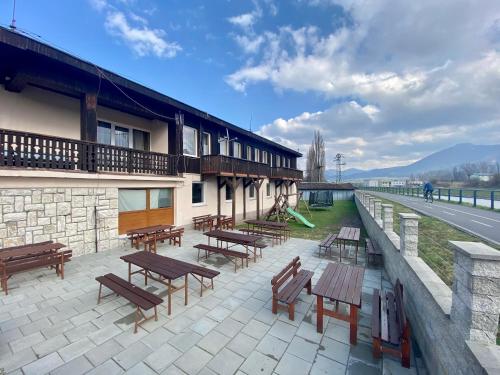 a patio with wooden tables and benches next to a building at Hotel Lodenica in Liptovský Mikuláš