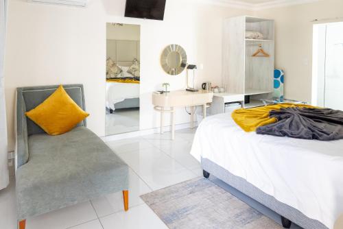 a bedroom with a bed and a yellow pillow and a chair at Prisatt Boutique Hotel in Onverwacht