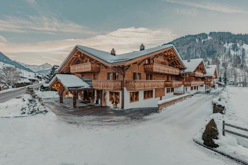 a large wooden house with snow on the ground at Ultima Hotel Gstaad in Gstaad