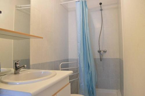 La salle de bains est pourvue d'un lavabo et d'un rideau de douche bleu. dans l'établissement SP480-166 Maison 2 pièces mezzanine SAINT PIERRE LA MER, à Saint Pierre La Mer