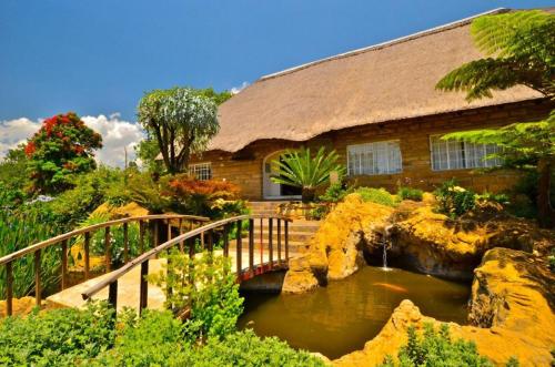 a house with a bridge over a pond in front at Hlalanathi Drakensberg Resort in Bergville