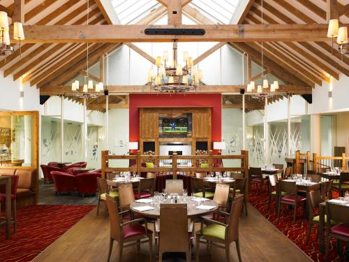 una sala da pranzo con tavoli, sedie e lampadario a braccio di Dalmahoy Hotel & Country Club a Edimburgo