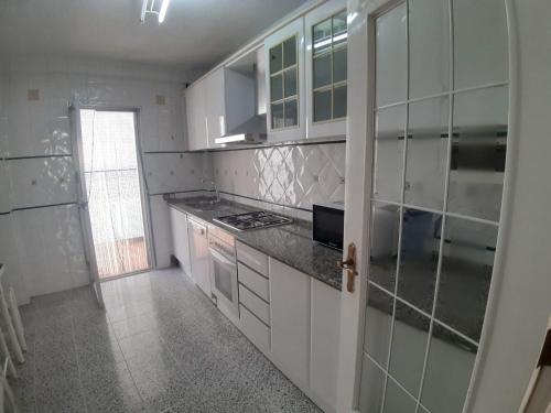 a kitchen with white cabinets and black counter tops at Apartamento Cerca Estacion de Bus in Murcia