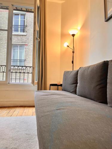 un salon avec un canapé et une fenêtre dans l'établissement Spacious flat near Montparnasse Bausset 4th, à Paris
