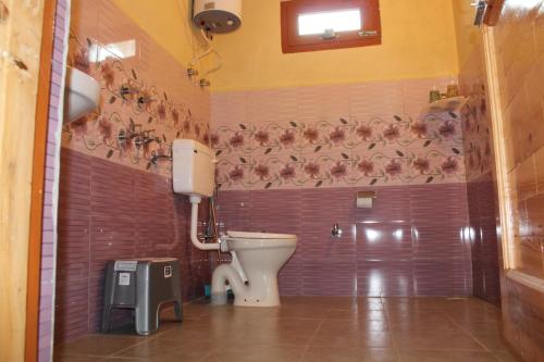 a bathroom with a toilet and chickens on the wall at MudHouse Retreat, Sarajara in Bīr