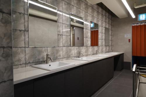 a bathroom with three sinks and two mirrors at Bluedot Poshtel in Seoul