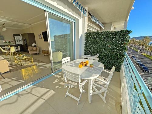- une table et des chaises blanches sur le balcon d'une maison dans l'établissement Sea Front Condo Promenade, à Nice