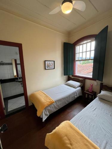 a bedroom with two beds and a window and a mirror at A Casa do Passo in Mariana
