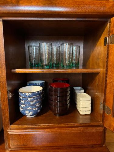 a cupboard filled with bowls and plates at Hakuba Riverside Loghouse in Hakuba