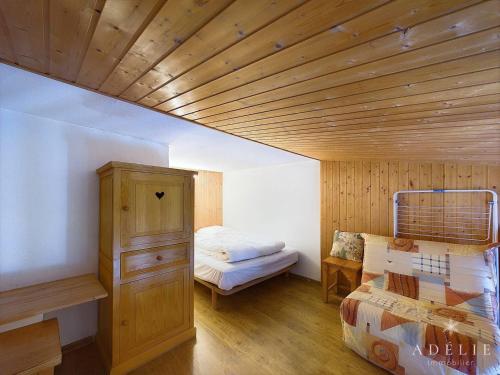 une chambre avec un lit et un plafond en bois dans l'établissement Studio mezzanine cosy, 4/5 pers, à 80m des pistes, balcon, TV/DVD, kichenette équipée - FR-1-398-553, à La Rosière