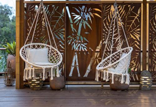 two chairs hanging from chains on a porch at Little Fish - Luxury Retreat in Yallingup in Yallingup